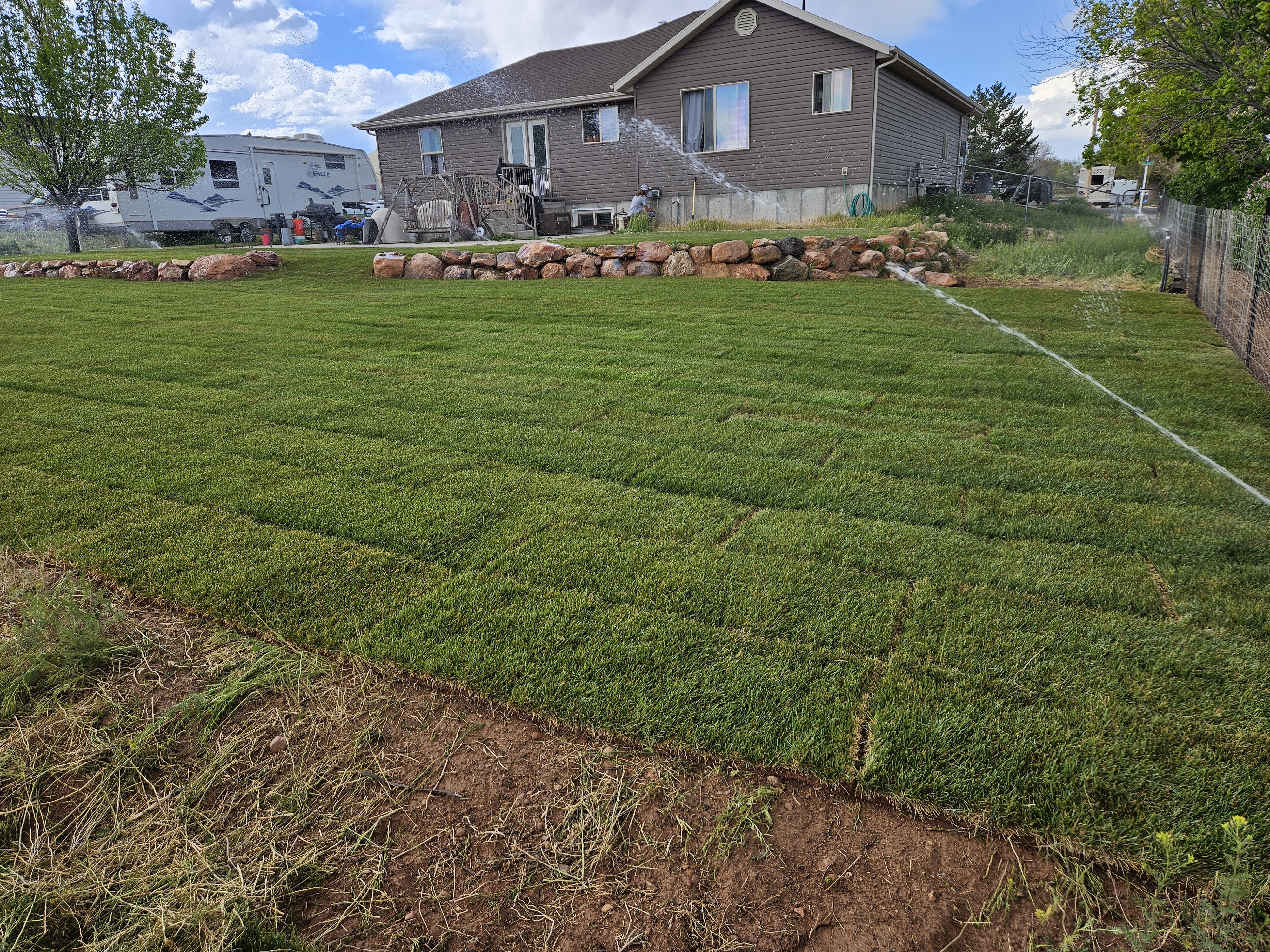 Freshly installed landscape beds along a home foundation with seasonal plantings and mulch